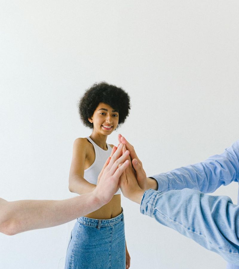 A diverse group of people smiling in a bright, modern yoga studio.