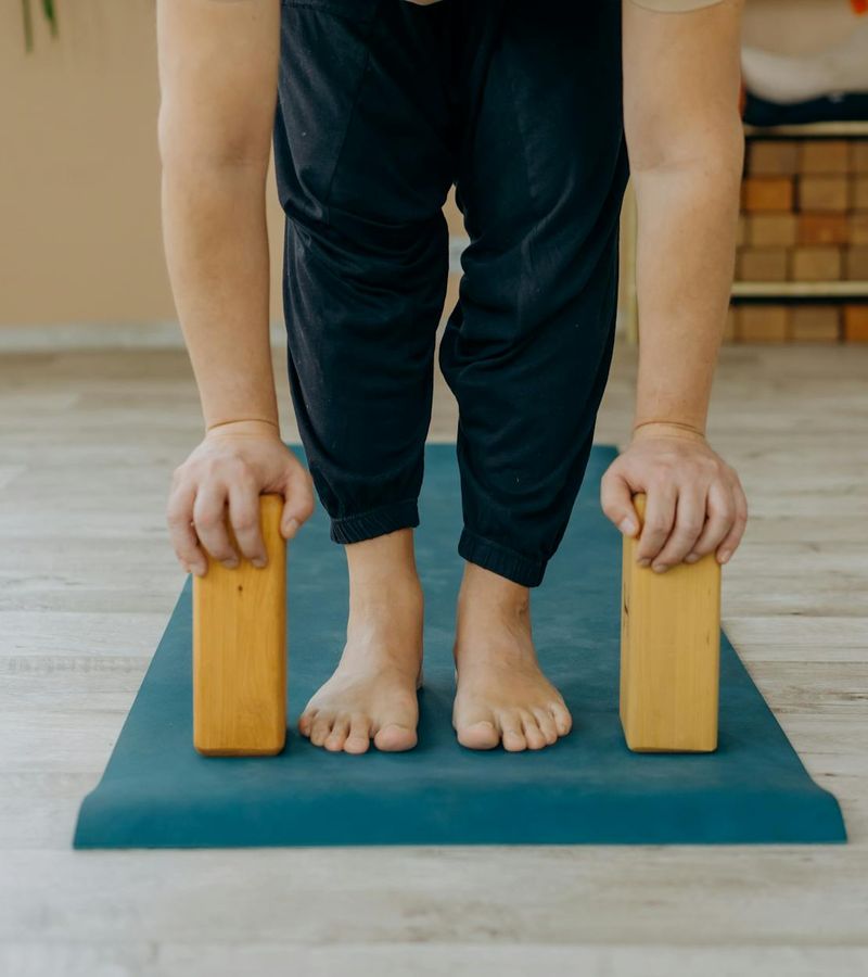 Person doing a stretching yoga pose on a mat in a bright studio.